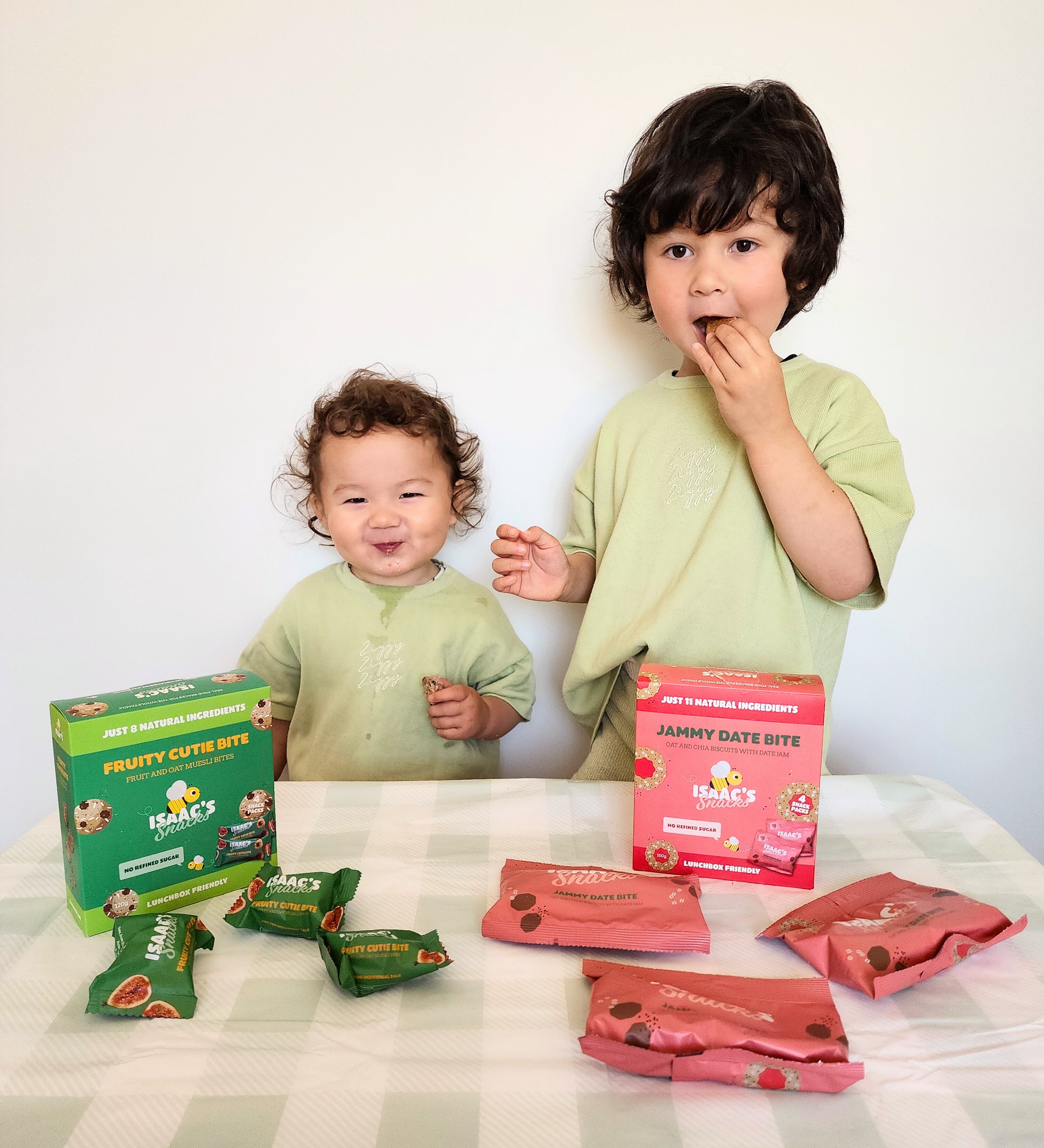 Two children with boxes and packets of 'Fruity Cutie Bites' on a checkered tablecloth.