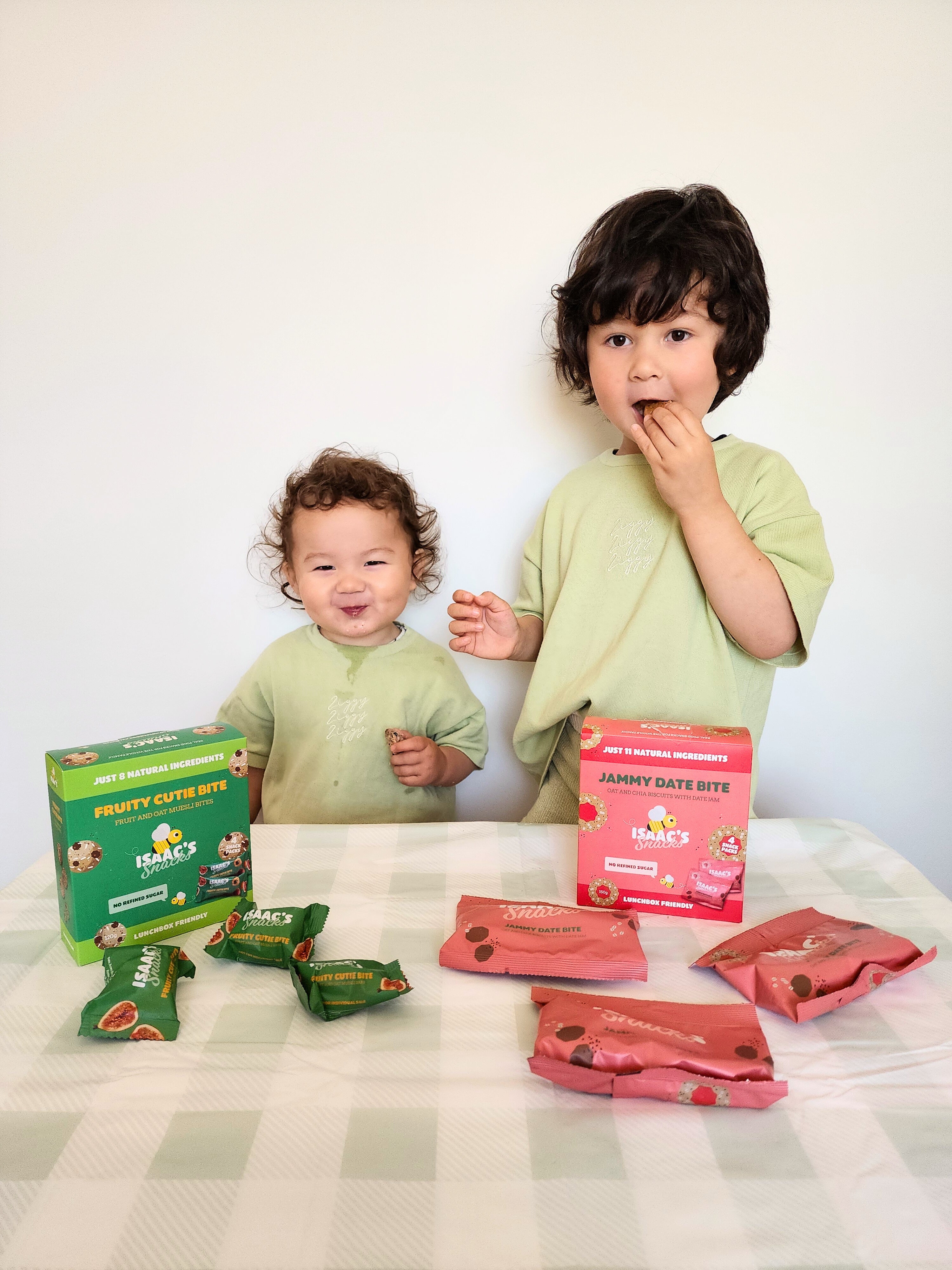 Two children with boxes and packets of 'Fruity Cutie Bites' on a checkered tablecloth.